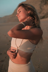 Model am Strand mit Yogaschmuck und Malaketten